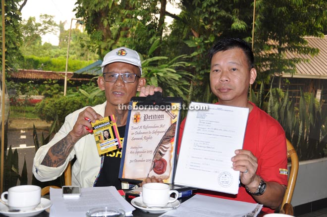 Tan (right) and Peter show the petition booklet at the press conference.