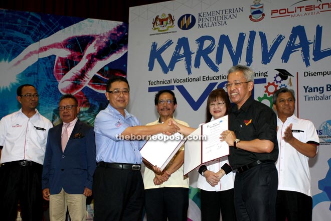 Amir (second right) exchanging documents with the Sabah Human Resource Department director, Kamal Pardi (third left) at the event yesterday. The exchange was witnessed by Mary (third right).