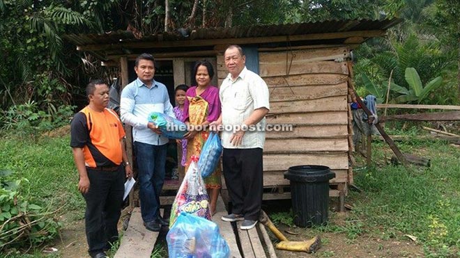 Sulaiman presents aid to Siti Fariza. Also seen are Haw (right) and Singap. 