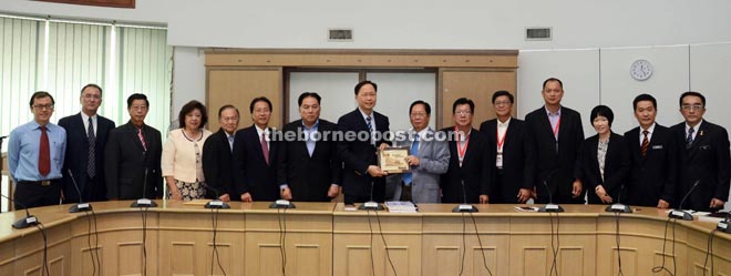 Lau (seventh right) presents a souvenir to Teo while delegates from Dong Zong look on. 