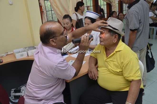 Dr Reddy conducts an eye examination on Pemanca Surat Asa of Long Bangan at  Sungai Asap Health Clinic.