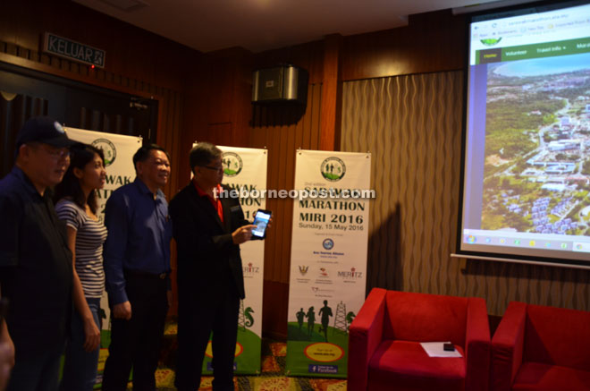 Sarawak Sports Corporation CEO Dr Ong (right) launching the marathon using a smart phone.