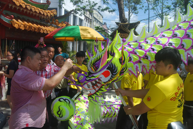 Ting (left) performs the dragon eye-dotting ceremony in front of the Tua Pek Kong Temple. At second left is Yung.