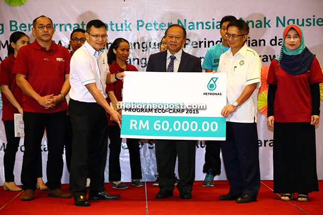 Richard (second left) presents a mock cheque to Peter, witnessed by Nansian (centre) and others. — Photo by Muhammad Rais Sanusi 