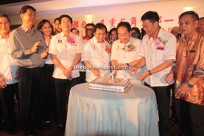 Wong (third right) cutting the first anniversary cake of UPP Batu Kawah branch, while Dr Jerip (fourth right), Liu (second right), Rayong (fourth left) and others look on. — Photo by Jeffery Mostapa