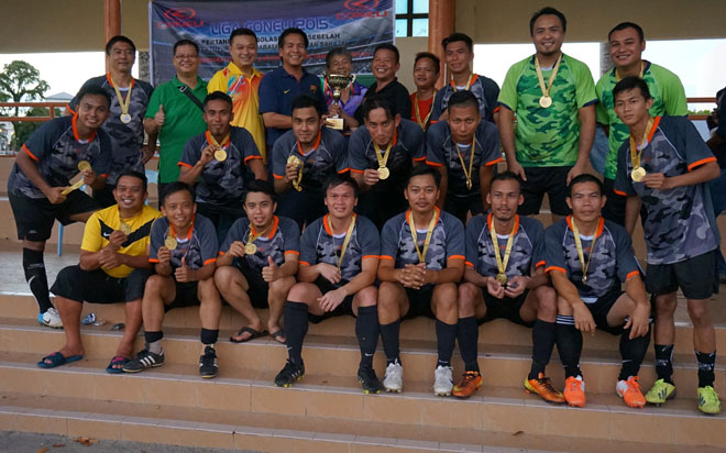 Dennis (last row, seventh right) gives away the champion trophy to team Wisma 2 after they beat IPD Miri in the final of the 2015 11-a-side Coneli Football League on Sunday.