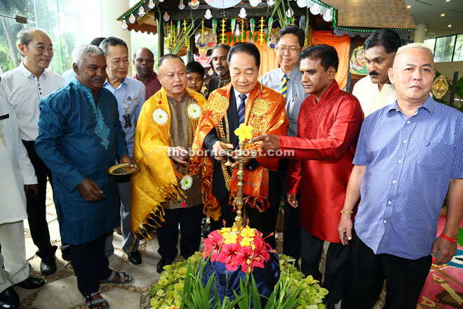 Wong (centre) lighting the Deepavali lamp to mark the celebration, assisted by Parthiben (on his left) while Chan (on his right) as others look on. — Photo by Rais Sanusi