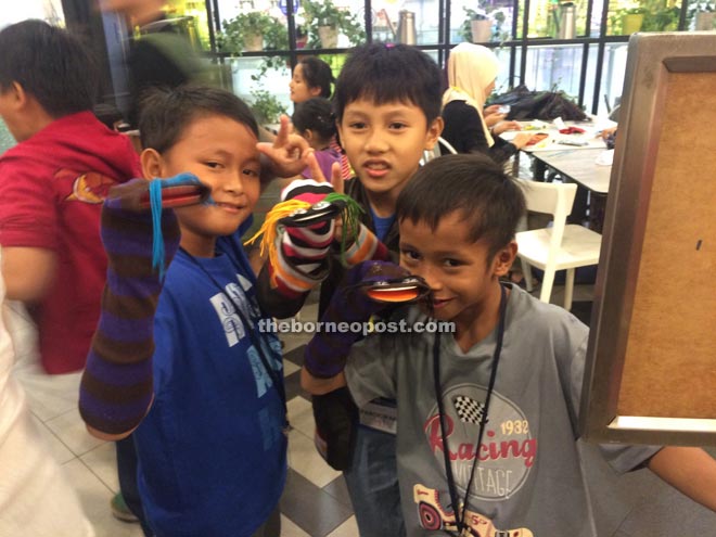 Three boys proudly showing off their sock puppets. 