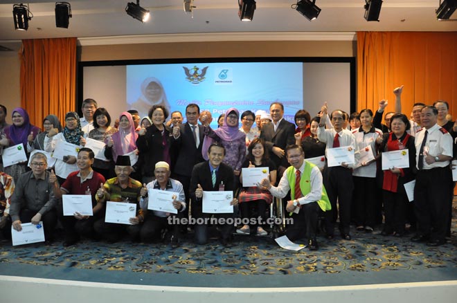 Fatimah (standing centre), flanked by Robert (on her right) and Shamsur, poses with recipients of the Petronas CSR grants after the handing-over ceremony at Wisma Bapa Malaysia.