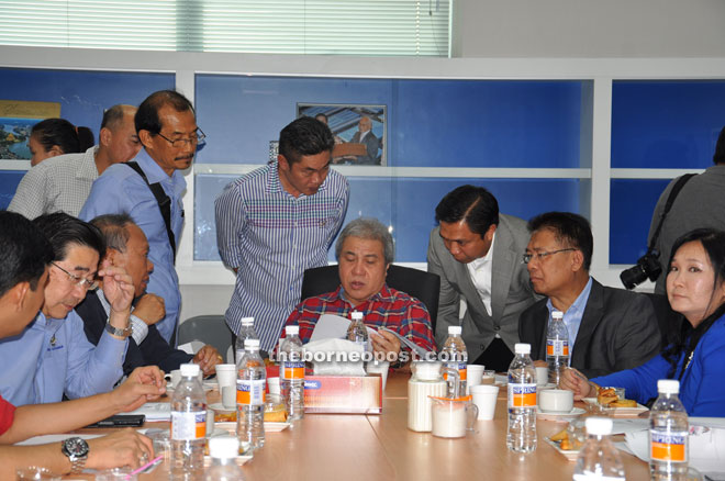 Awang Tengah (seated centre) studies detailed information of the plant. Also seen are Nansian (seated, third left), Julaihi (seated second right) and Kow (right) during the briefing.