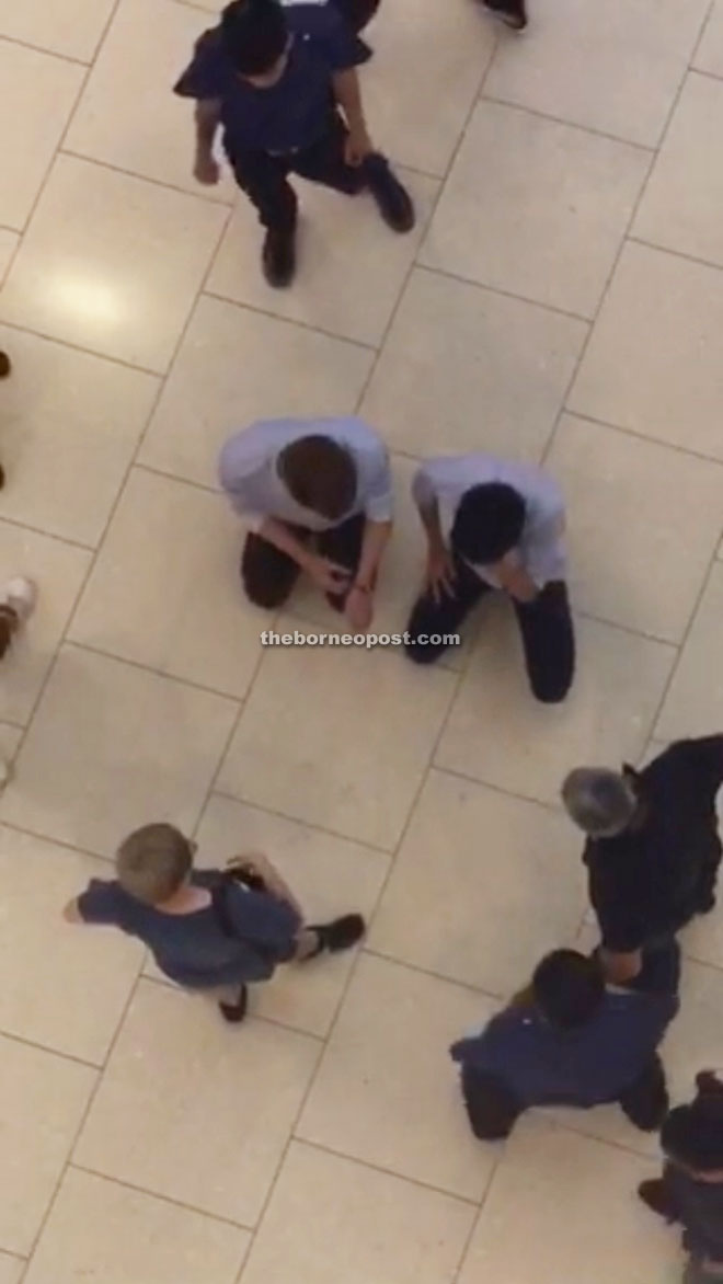 A screengrab from the video showing the two male youths being forced to kneel in front of their colleague.