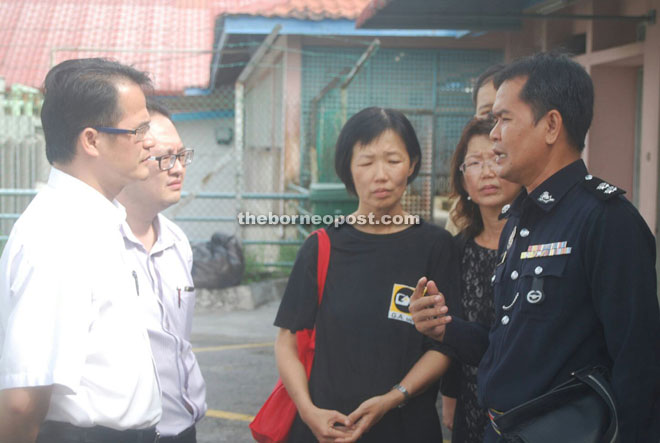 Yap (left) speaks to the police investigating officer Wilson while looking on at centre is the deceased wife Ting Leh Ung, 46.