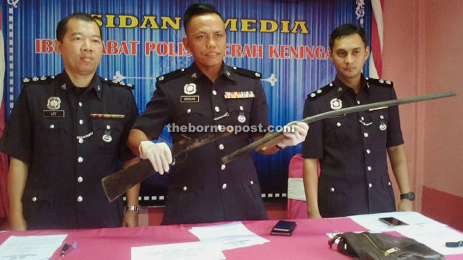 Douglas (centre) showing the homemade gun. Also seen was the CID Chief, ASP Lee Nyuk Kim (left) and an Investigating Officers.