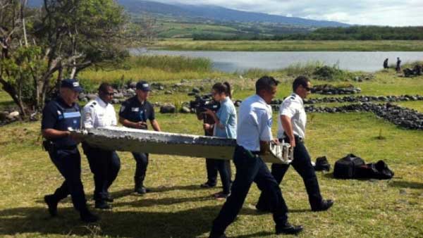 Police carry a piece of debris from an unidentified aircraft found in the coastal area of Saint-Andre de la Reunion on July 29, 2015. – AFP File Photo 