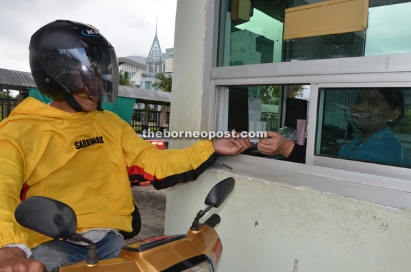 A motorcyclist paying his toll. 