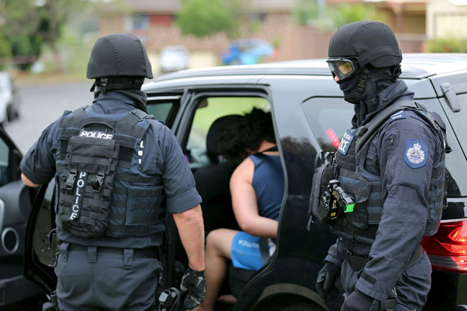 Heavily armed police officers detain a man during early morning raids in western Sydney, Australia in this handout courtesy of New South Wales (NSW) Police. Australian police said they had charged a 20-year-old man and a 15-year-old boy with conspiracy to conduct an act of terrorism after they were arrested during early-morning raids in Sydney yesterday. — Reuters photo