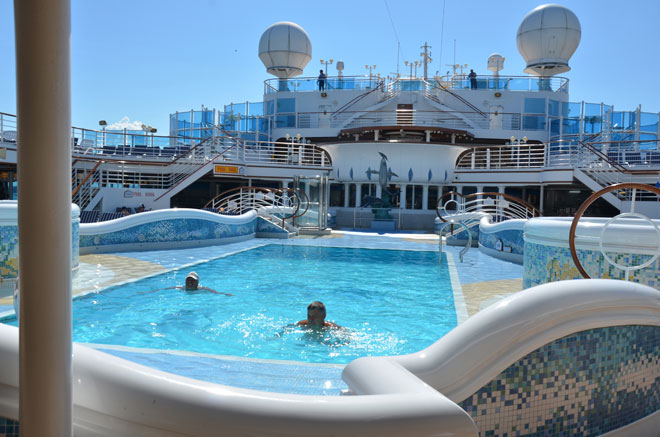 Cruise guests swimming on the top deck of the ship.