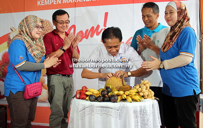 SIMBOLIK: Paza (tengah) membuka durian sebagai simbolik perasmian Kempen Makan Buah-Buahan Tempatan di Medan Niaga Satok semalam.