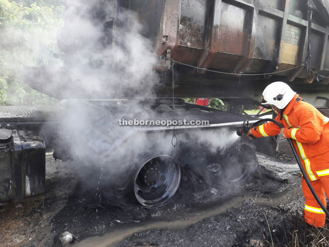 A firefighter drenches the rear of the lorry to extinguish remaining flames.