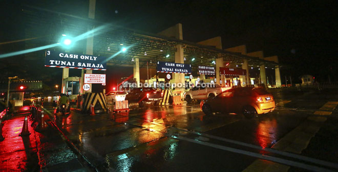 Vehicles entering Petra Jaya via the Tun Salahuddin Bridge stopping to pay toll at the toll plaza last night.