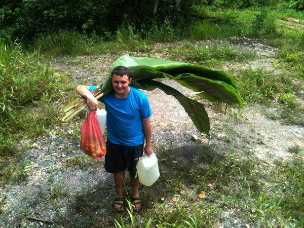 Anatoliy brings back some supplies gathered from the nearby jungle for a makeshift shelter.