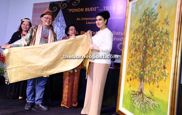 Ong (left) presenting a shawl to Raghad as a souvenir after she launched the Tree of Life exhibition while Tourism Assistant Minister Datuk Gramong Juna’s wife Datin Catherine Gramong (centre) looks on. — Photos by Muhammad Rais Sanusi