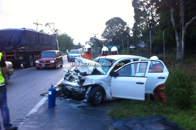 Firefighters work to extricate one of the victims from the badly-damaged car. 