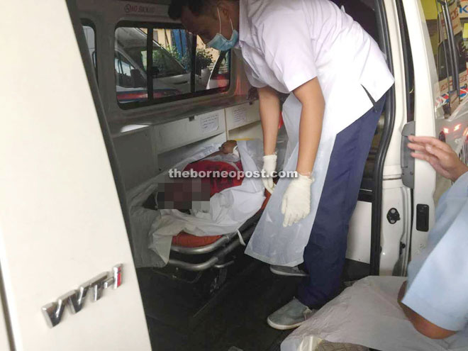 A medical personnel inspects the body of the deceased upon arrival at Sarawak General Hospital.