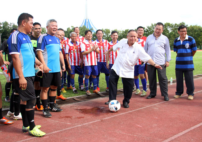 Chan (centre) performs the kick-off for the friendly match yesterday as the invited guests, officials and players look on at Jubilee Ground yesterday. — Photo by Chimon Upon