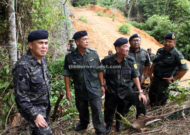 Fuad (left) looks at the cleared jungle – a stone’s throw away from the Tebedu/Entikong ICQ – believed to be an illegal entry point by foreigners into the state. — Photo by Chimon Upon