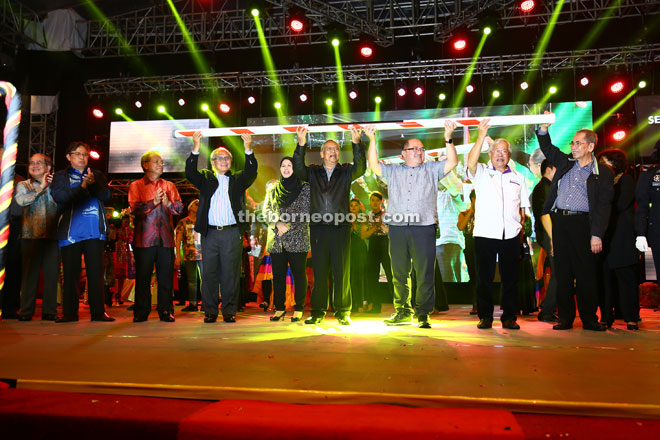 Adenan (fourth right) and other dignitaries lifting the toll bar to symbolise the end of the toll system in Sarawak. Also seen in the photo is Jamilah (fifth left). — Photo by Muhammad Rais Sanusi