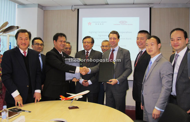 Pahon (third left) and Burke shake hands after signing the documents, witnessed by Abang Johari (fifth left). Also seen are Gramong (fourth left), Talib (sixth left) and others.