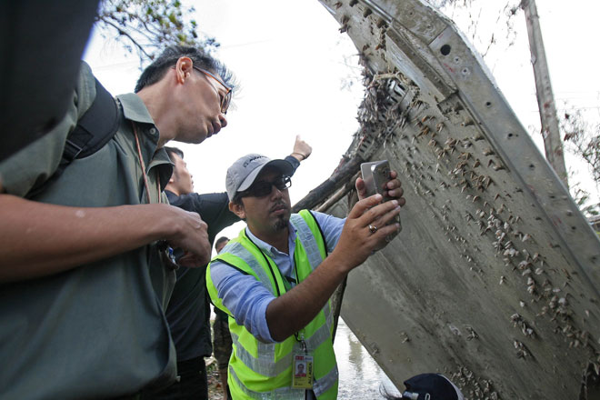 A Malaysian official takes pictures of a piece of suspected aircraft debris after it was found by fishermen on Saturday at a beach in the southern province of Nakhon Si Thammarat. — AFP photo 