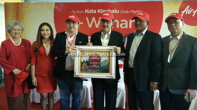 Lee (third left) presenting a memento to Masidi at the inaugural ceremony of AirAsia’s Kota Kinabalu and Wuhan route here yesterday. 2, 3 & 4. Masidi handing over goodie bags to travellers of AirAsia’s inaugural Kota Kinabalu to Wuhan flight at Kota Kinabalu International Airport here yesterday.