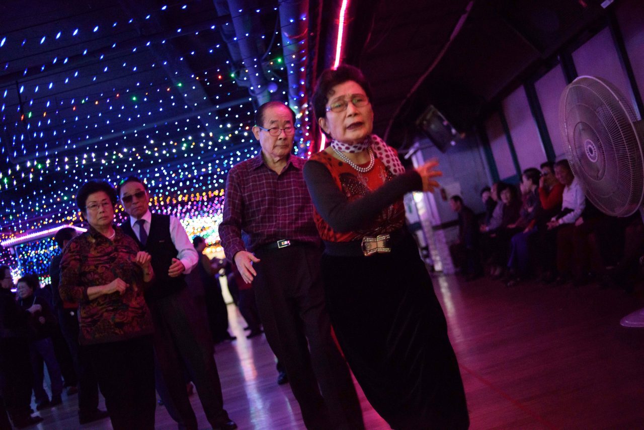 TO GO WITH AFP STORY: SKorea-lifestyle-culture-population-ageing, FEATURE by Jung Ha-Won In a photo taken on December 2, 2015 a couple dance at a 'colatec' in Seoul. As the mercury outside plunges to minus 10 degrees on an ice-cold Monday afternoon, the dance floor inside the Kukilgwan Palace is packed with gray-haired Korean couples moving to the rhythms of high-volume disco. South Korea's rapidly ageing population may be a major headache for policymakers, but its members are determined to enjoy themselves, dancing the years away at clubs where 50-year-olds are turned away for being "too young." Colatecs first emerged in the late 1990s as dance halls for teenagers, where alcohol was banned and the only drinks on offer were sodas like Coca Cola. But they soon fell out of fashion with their young clientele which migrated to gatherings at Internet cafes and karaoke clubs. And so the Colatecs rebranded themselves for an entirely different demographic. AFP PHOTO / Ed Jones