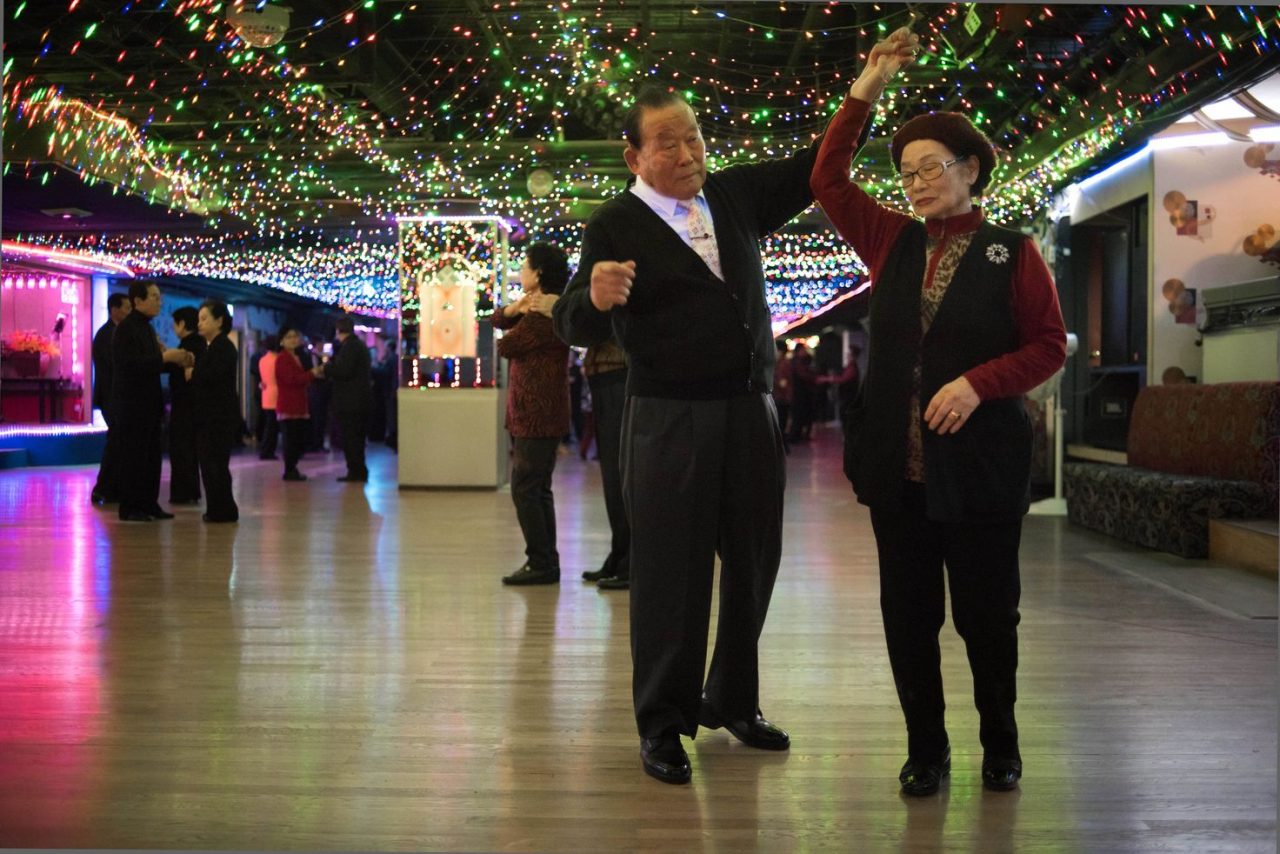 TO GO WITH AFP STORY: SKorea-lifestyle-culture-population-ageing, FEATURE by Jung Ha-Won In a photo taken on December 2, 2015 a couple dance at a 'colatec' in Seoul. As the mercury outside plunges to minus 10 degrees on an ice-cold Monday afternoon, the dance floor inside the Kukilgwan Palace is packed with gray-haired Korean couples moving to the rhythms of high-volume disco. South Korea's rapidly ageing population may be a major headache for policymakers, but its members are determined to enjoy themselves, dancing the years away at clubs where 50-year-olds are turned away for being "too young." Colatecs first emerged in the late 1990s as dance halls for teenagers, where alcohol was banned and the only drinks on offer were sodas like Coca Cola. But they soon fell out of fashion with their young clientele which migrated to gatherings at Internet cafes and karaoke clubs. And so the Colatecs rebranded themselves for an entirely different demographic. AFP PHOTO / Ed Jones