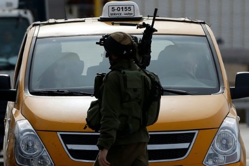 AFP | An Israeli soldier checks the vehicles of Palestinians on their way out of the West Bank village of Ein Sinya, northern Ramallah on February 1, 2016 