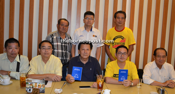 SUPP Bukit Assek branch chairman Chieng Buong Toon (seated centre) and Pelawan branch secretary Michael Tiang (seated second right), showing the BN constitution booklet, while Dudong branch chairman Datuk Dr Soon Choon Teck (right) and chief publicity secretary for SUPP State Election Committee Wong Ching Yong and others look on.