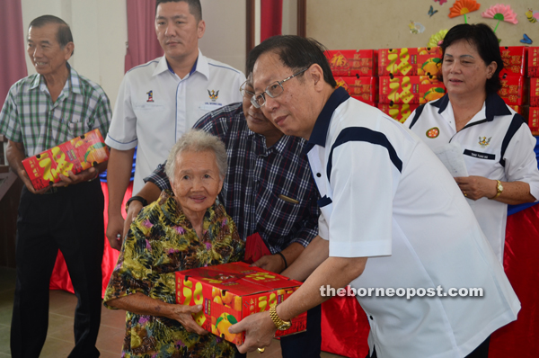 Temenggong Dato Lau hands over CNY gifts to a senior citizen at Ung Nang Primary School in Bukit Lan. 