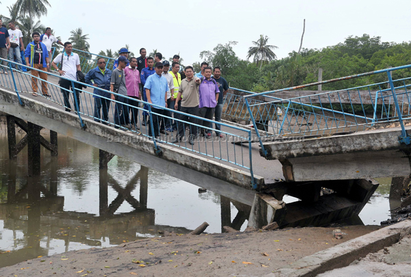 TIDAK SELAMAT: Hasni (kiri) diiringi Maulizan (dua kiri) meninjau keadaan jambatan sepanjang 50 meter di Kampung Perigi Acheh, Pasir Gudang yang runtuh kelmarin di Johor Baharu. — Gambar Bernama