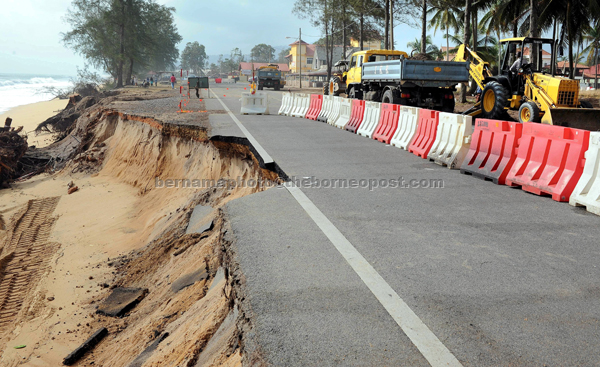 AKIBAT FENOMENA ALAM: Traktor dan jentera berat digunakan menambak semula tebing pantai yang runtuh membabitkan juga beberapa batang pokok akibat hakisan dibadai ombak besar di Jalan Pantai Teluk Lipat di Dungun, semalam. Jalan ini ditutup kepada semua kenderaan berikutan sebahagian tebingnya runtuh sehingga ke bahagian jalan sepanjang 100 meter dipukul alun besar fenomena air pasang besar sejak tiga hari lepas. — Gambar Bernama