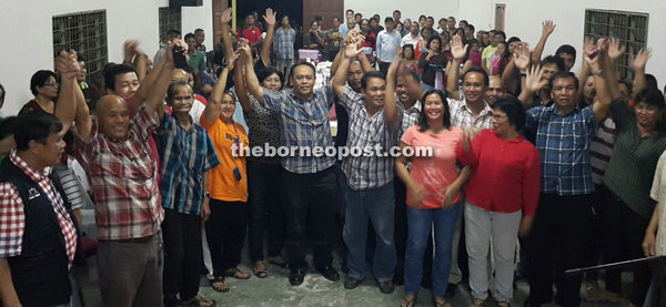 Henry (middle) and others raise their hands for a photo call at Kampung Serikin.