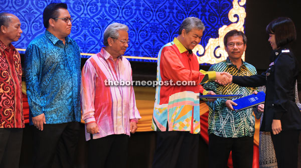 Zahid presents a certificate to a recipient. He is flanked by Masing (left) and Alwi. Masir is seen at left.