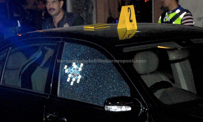 Police personnel inspecting the car with bullet holes at Jalan Dato Kramat, George Town. — Bernama photo