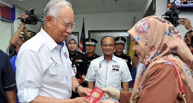Najib handing over a passport to a applicant at Labuan Urban Transformation Centre (UTC) after the launching of the centre yesterday. The RM26 million project, with better safety feature is strategically located at the cozy but busy area of the modern Labuan Central Market building and bus and tax terminal.— Bernama photo