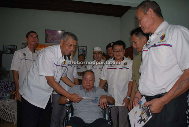 Anwar (left) presents the one-off payment to Nigeng as others look on.