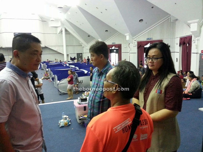 See (left) and Voon (right) listening to Jawa (third left) explain the flood situation at Kpg Kudei when they visited the flood victims at Kuching Civic Centre. 