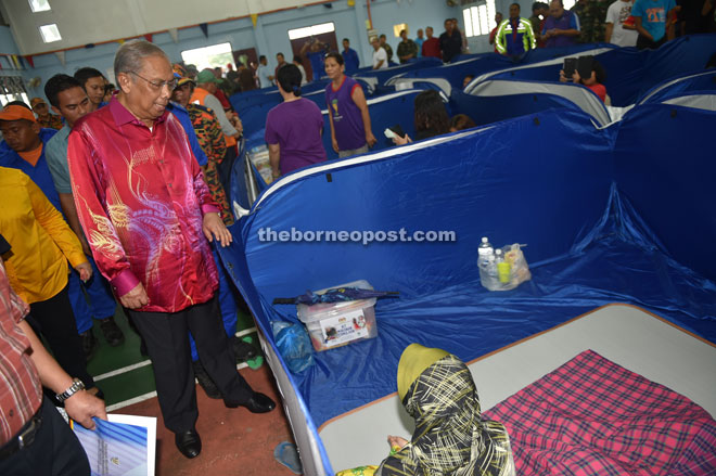 Adenan (left) looking at one of the makeshift tents for the flood victims at the flood relief centre in Malihah on Monday. — Photo by Tan Song Wei