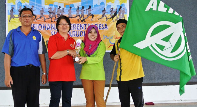 SMK Marudi senior assistant Puan Nurlaila presenting the Cross-Country Champion Trophy to the teacher in-charge of Achiever House.