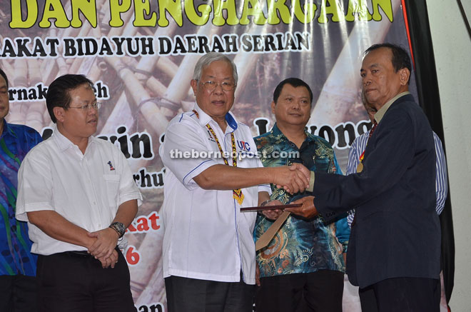 Manyin (second left) presents a certificate of appreciation to one of the recipients at the Serian Division Bidayuh Community Leaders Association appreciation and award presentation ceremony.